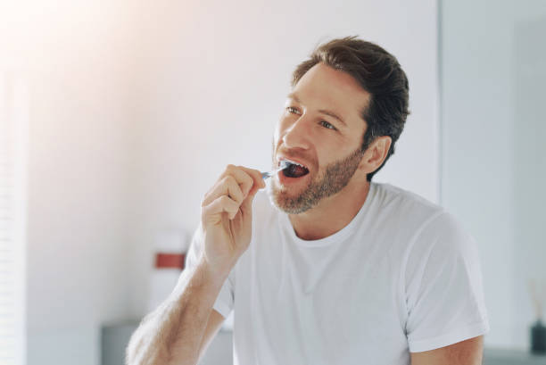 image of a man in a white shirt brushing his teeth