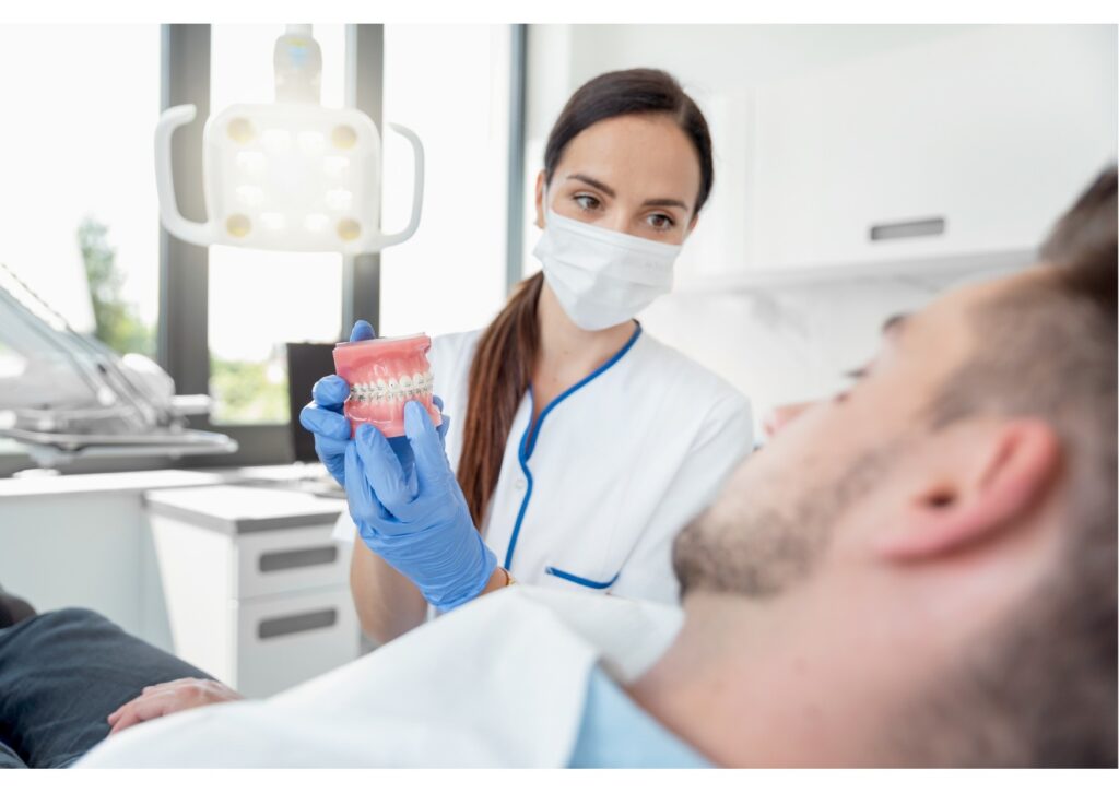 Dentist showing braces model to patient, dental insurance coverage concept
