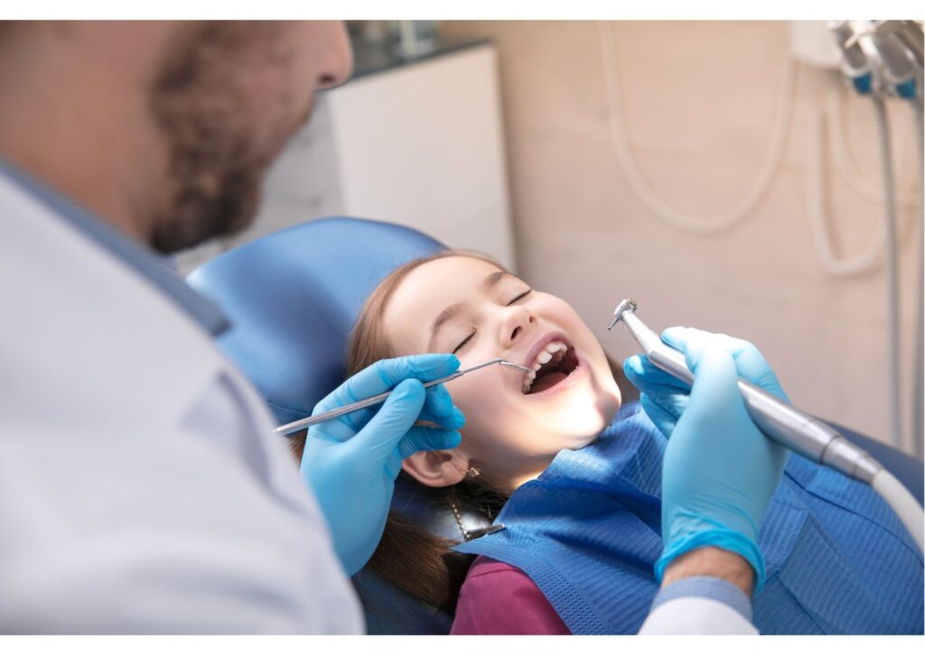 Dentist examining child’s teeth during routine checkup, first dental visit timing