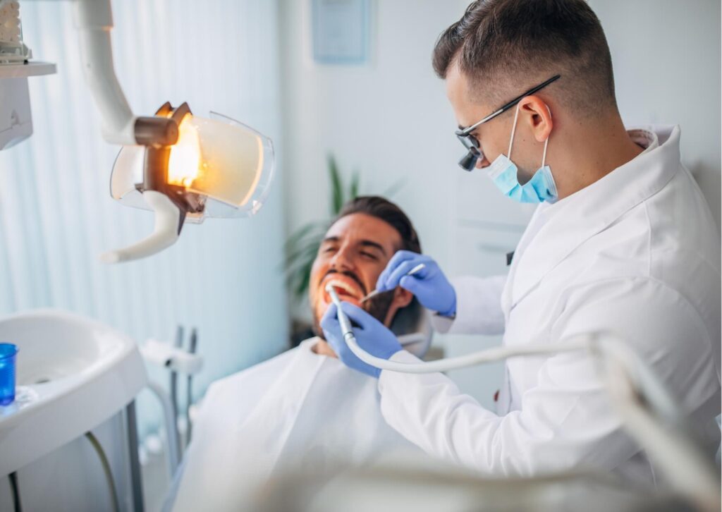 Dentist performing a professional dental cleaning on a patient to remove plaque and tartar as part of treatment for fixing gingivitis and restoring gum health.