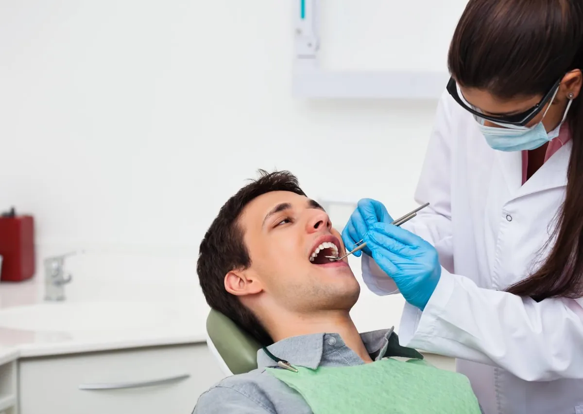 Dentist examining a patient’s teeth during a checkup to assess their complete set of adult teeth.