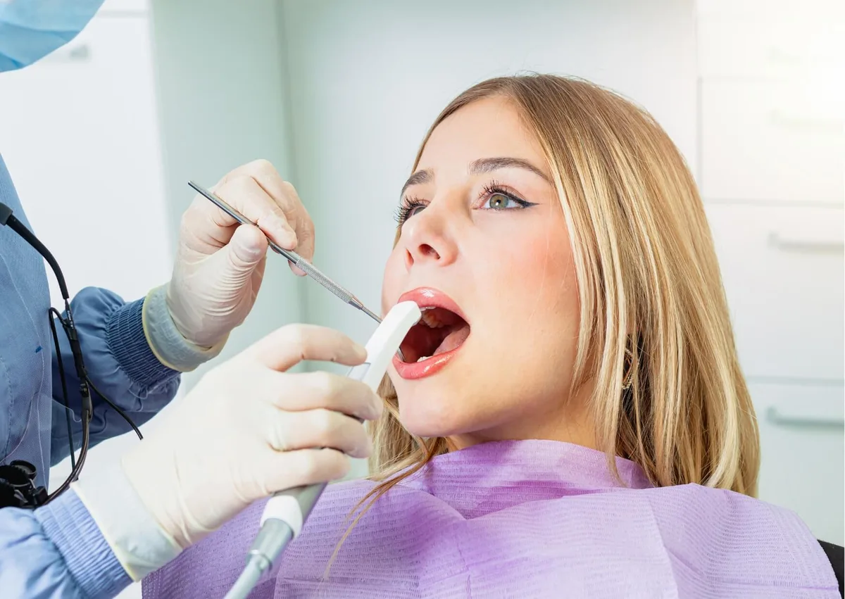 Dentist examining a patient’s mouth to check normal socket healing after tooth extraction.