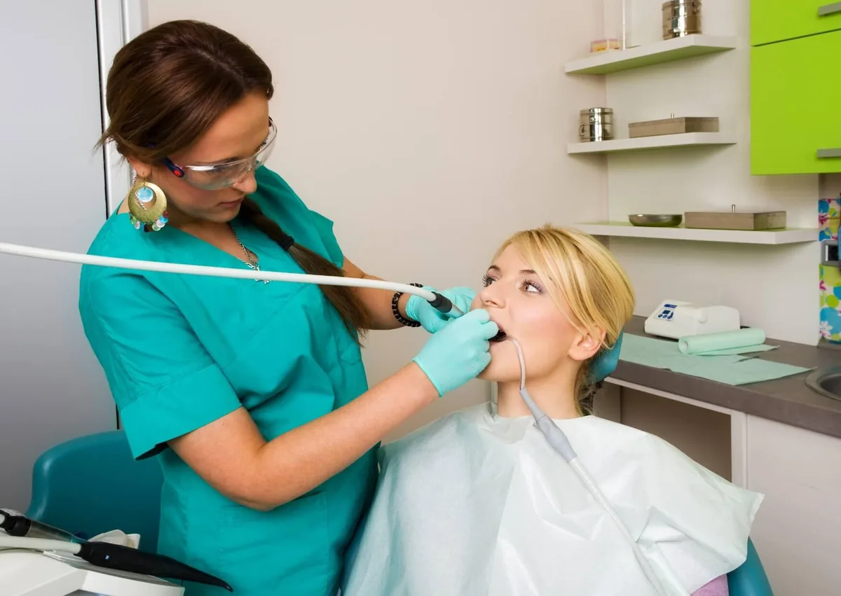 Dental hygienist removing plaque from a patient’s teeth during a professional dental cleaning.