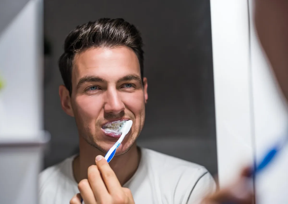Man brushing his teeth as part of oral care for swollen gums.