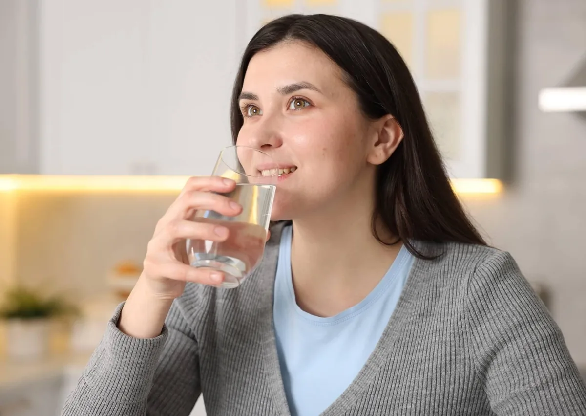 Woman drinking water to help relieve symptoms of persistent dry mouth.