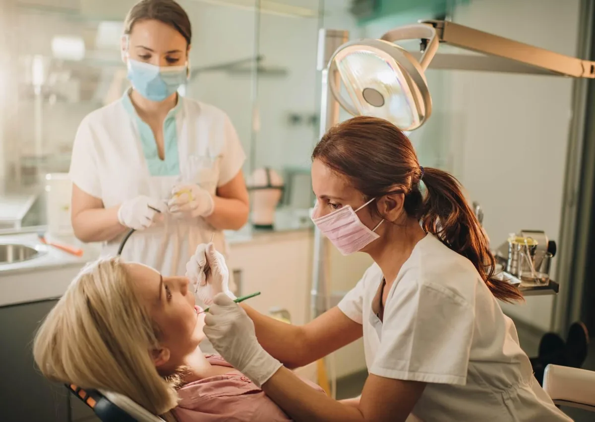 Dentist examining a patient's mouth for signs of oral thrush during a dental checkup.